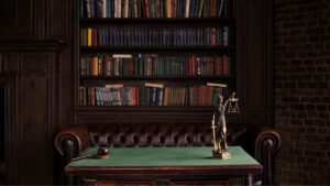 Cabinet avocat avec librairie au fond, bureau en premier plan et une balance de justice